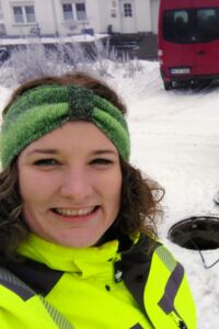 Selfie im Schnee vor einem geöffneten Schacht, der gerade untersucht wird