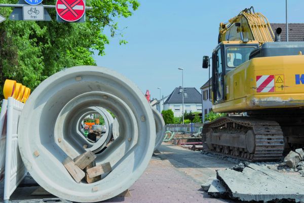Bagger bei Straßenbaumaßnahme mit Kanalrohr