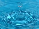 Ein Wassertropfen fällt in klares, blaues Wasser