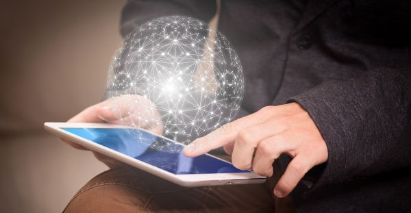 Nutzer arbeitet mit Tablet, auf dem ein kugelförmiges "Datennetz schwebt".