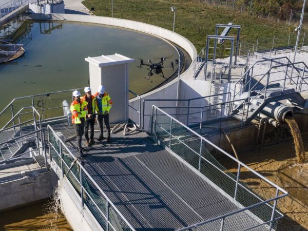 Ingenieure begutachten eine Kläranlage mit Hilfe einer Drohne