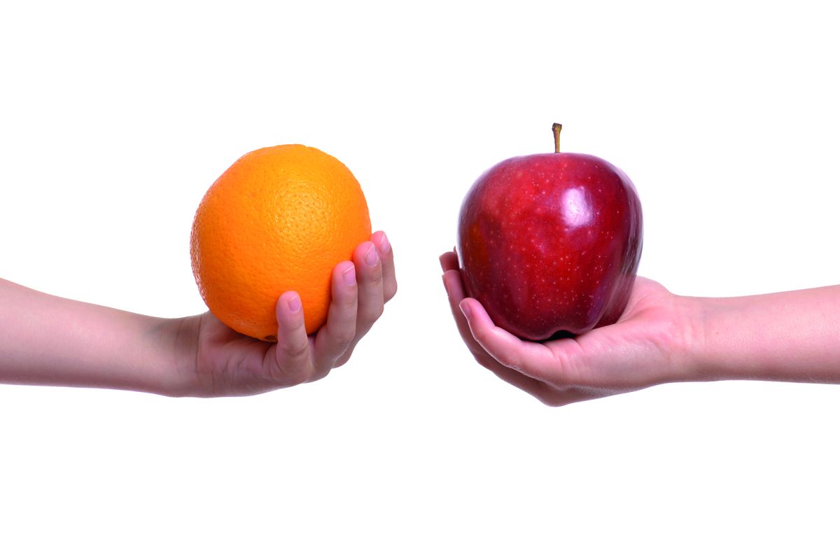 zwei unterschiedliche Hände halten zum Vergleich eine Orange und einen Apfel nebeneinander