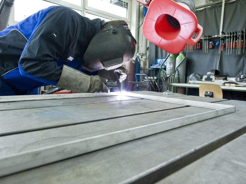 Person in Schutzkleidung beim Schweissen in der Werkstatt