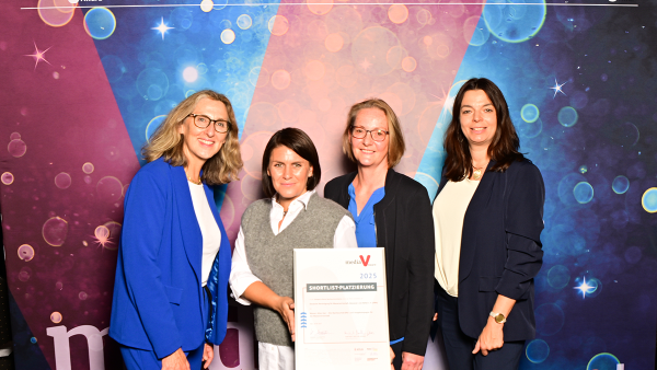 Gruppenfoto mit Nominierungsurkunde vor der Fotowand des media VAward