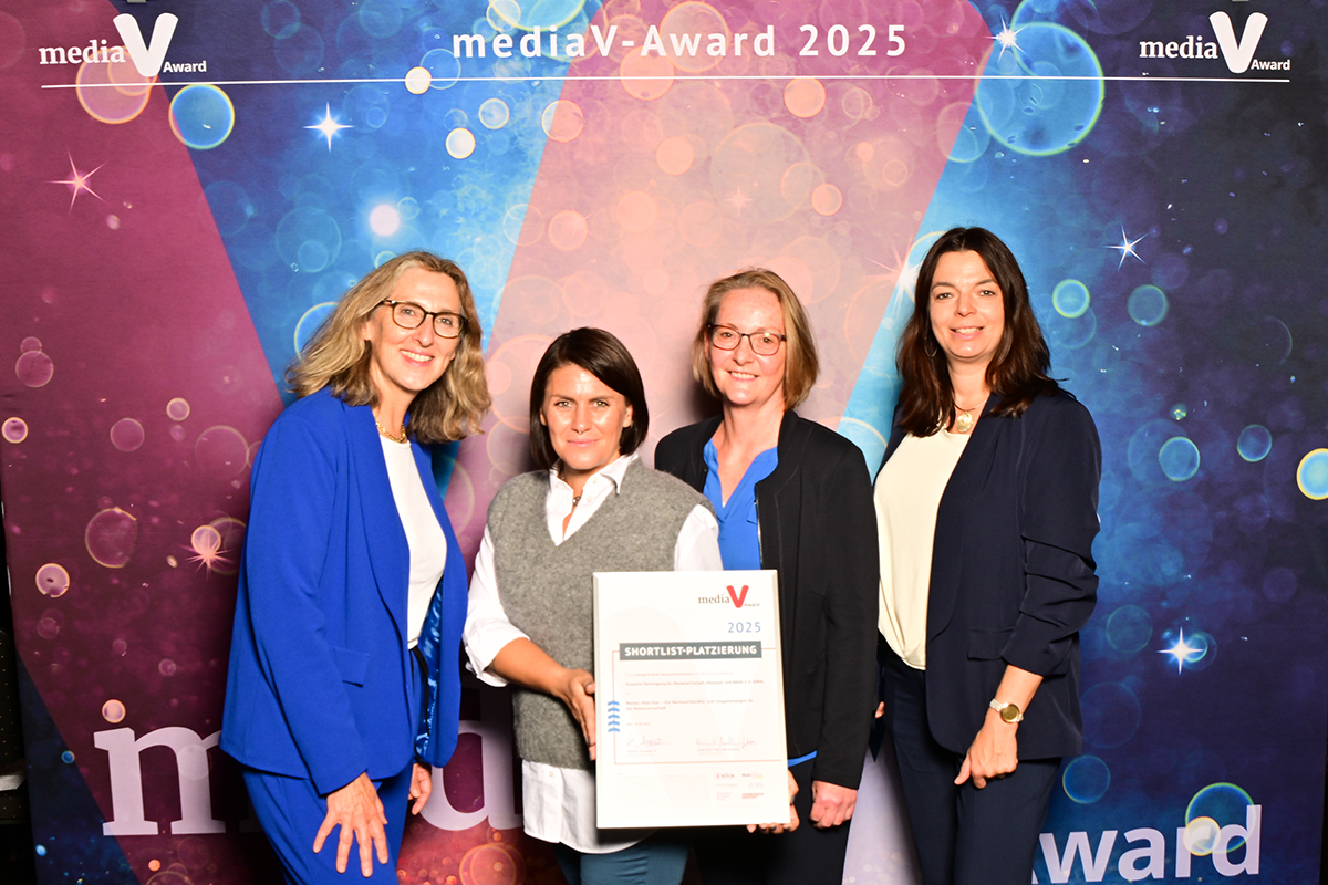 Gruppenfoto mit Nominierungsurkunde vor der Fotowand des media VAward